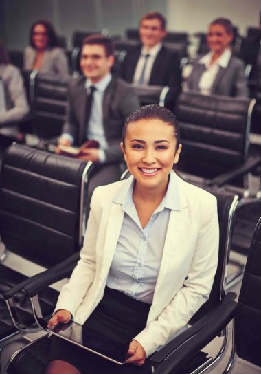 Image of business people sitting in rows at seminar with pretty woman in front